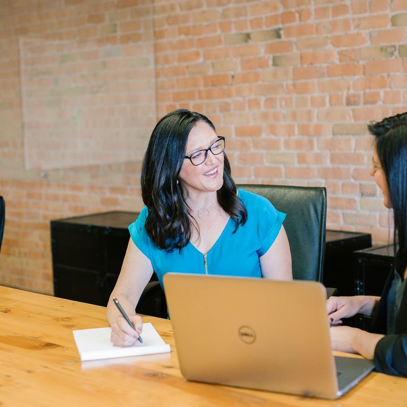 Consultant listening to a customer across a desk with a laptop