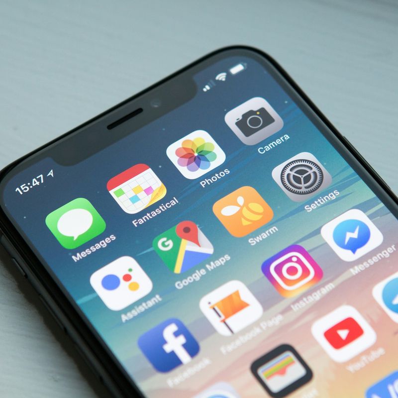 Hand holding a smartphone showing its home screen